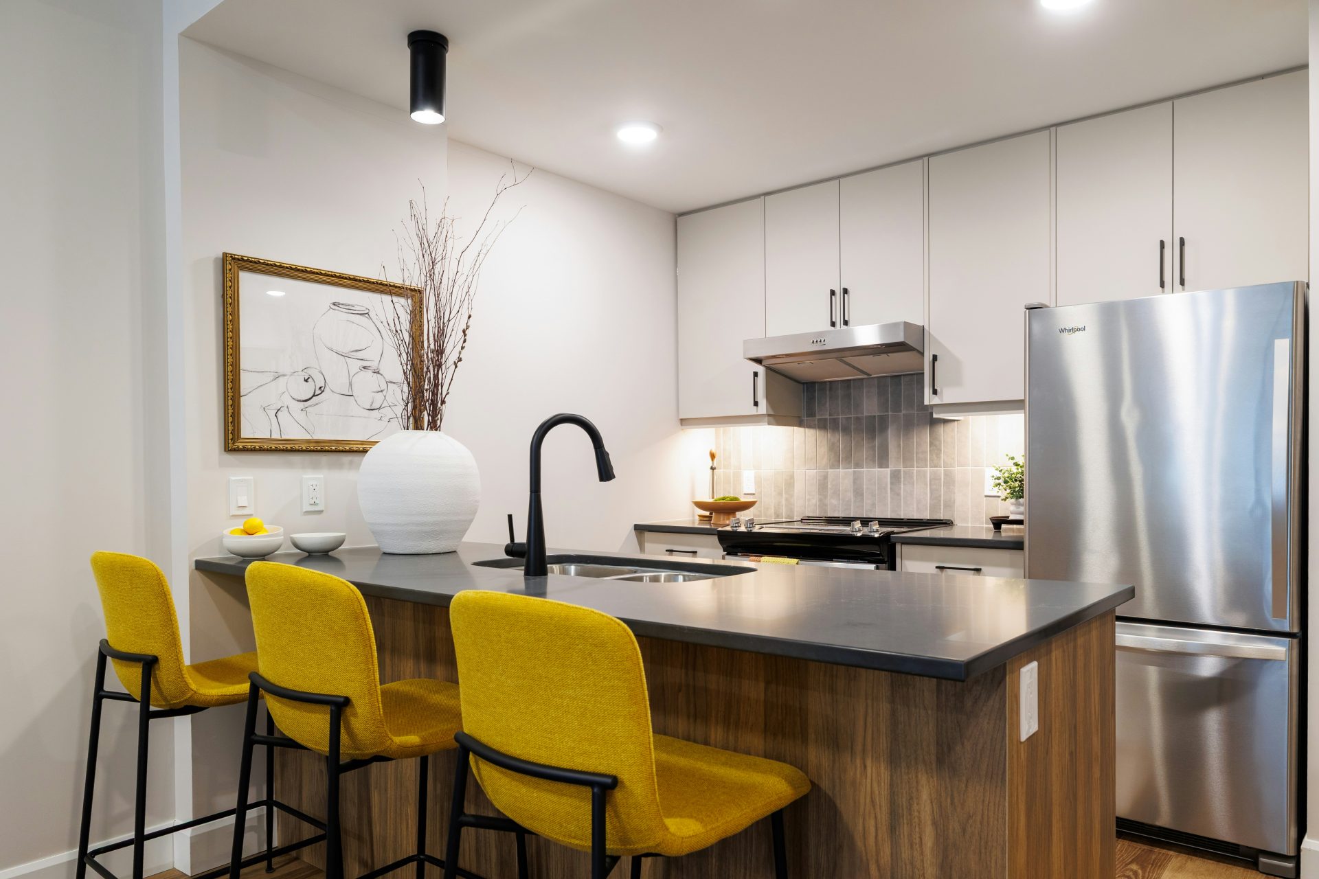 Cocina moderna con isla y taburetes amarillos.